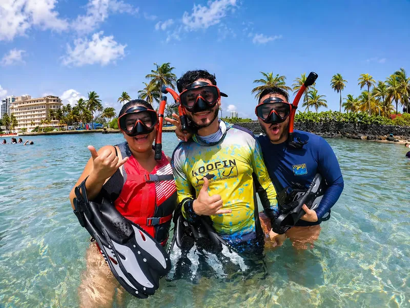 Beginner snorkeler following an instructor toward a green sea turtle at Escambron Beach, snorkeling in San Juan Puerto Rico