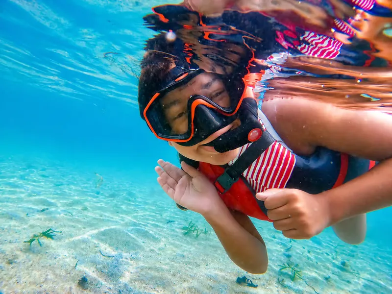 Family with young children snorkeling in shallow clear water at Escambron Beach on a kids-friendly San Juan Puerto Rico snorkeling tour
